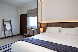 Una camera d'albergo con un letto grande, una scrivania, una sedia, un comodino e una finestra.