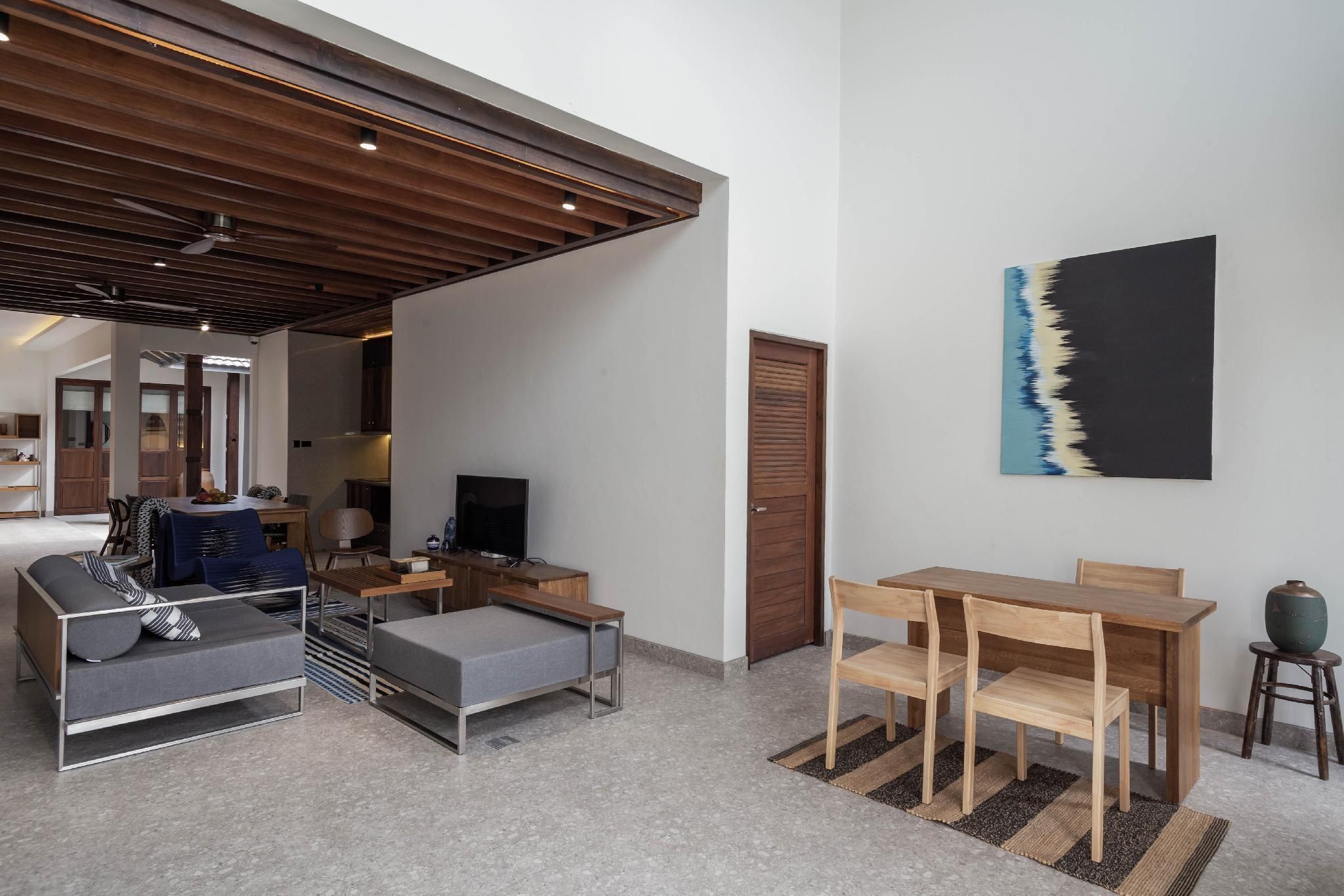 A modern living room with a sofa, a TV, a wooden dining table, and a painting on the wall.
