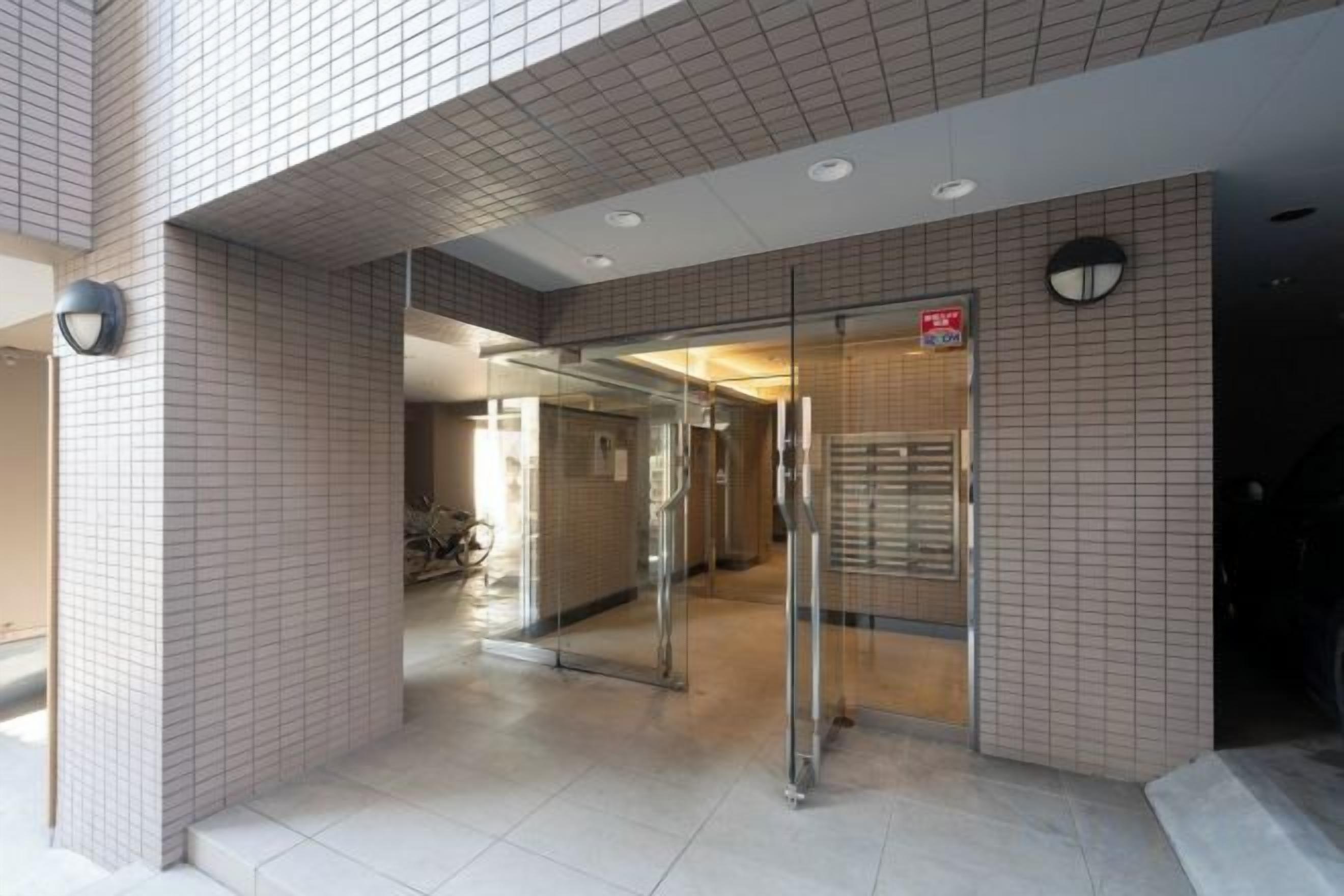 A building entrance with a tiled facade, a glass door, and a sign indicating a public area.