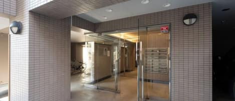 A building entrance with a tiled facade, a glass door, and a sign indicating a public area.