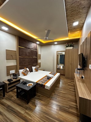 Une chambre d’hôtel moderne équipée d’un lit, d’une table de chevet, d’une télévision, d’une armoire et d’un petit bureau.
