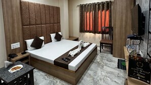 Una habitación de hotel con cama, escritorio, silla, ventilador de techo y aire acondicionado.