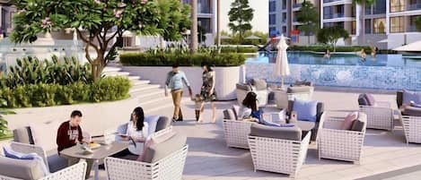 An outdoor seating area with wicker furniture, a pool, and a building with balconies.