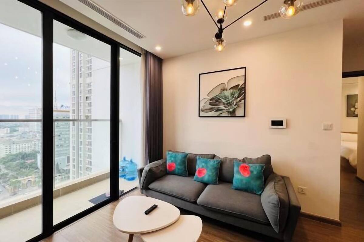 Ein modernes Wohnzimmer mit einer Couch, einer Fernbedienung und einem großen Fenster mit Blick auf die Stadt.