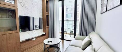 A modern living room with a sofa, a TV, a small round table, and a sliding glass door leading to an outdoor area.