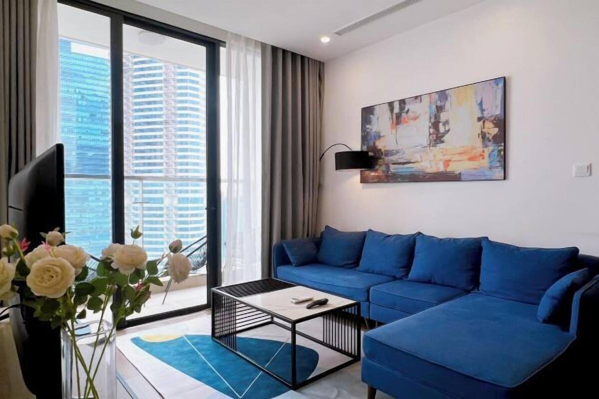 Ein modernes Wohnzimmer mit einem blauen Sofa, einem Couchtisch, einem Fernseher und einem Bild an der Wand.