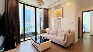 A modern living room with a sofa, a glass coffee table, and a television. - PQG - Vinhomes Skylake - Lavish - Resplendent Apartments in Hanoi (Hanoi)