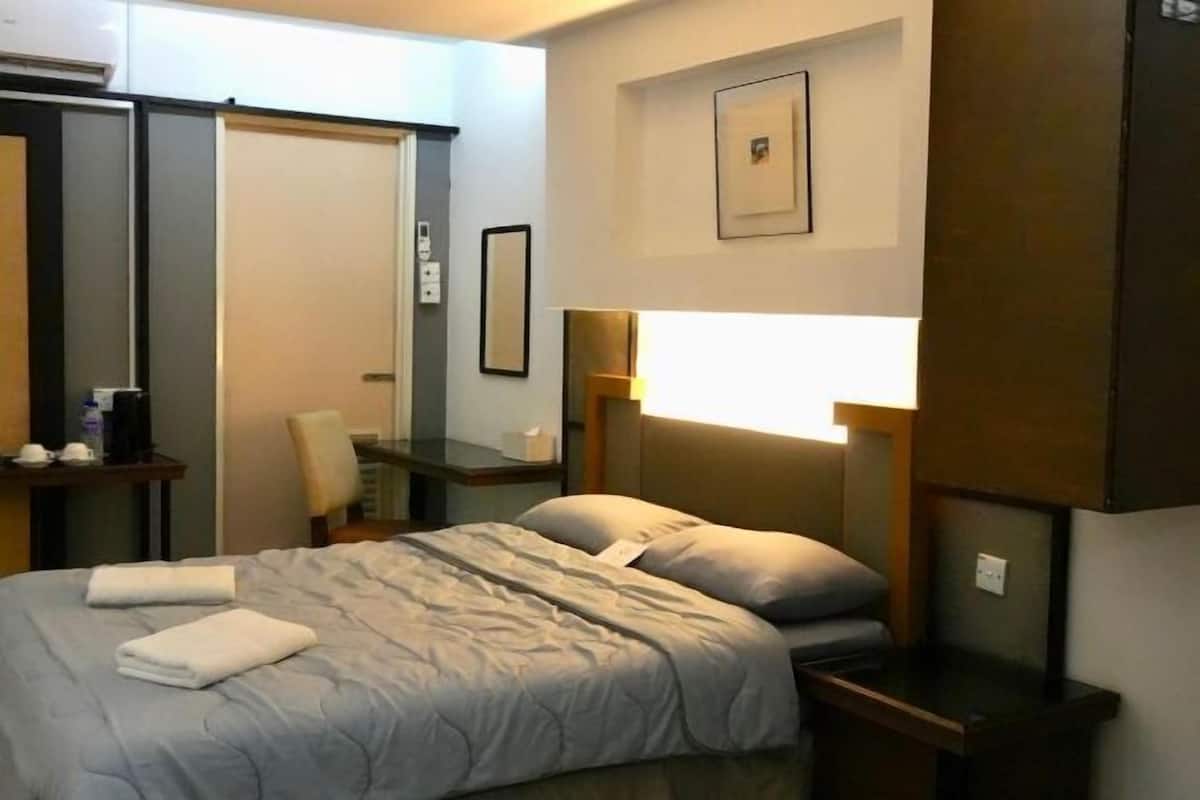 Une chambre d’hôtel comprenant un lit, une table de chevet, une chaise et une lampe fixée au mur.