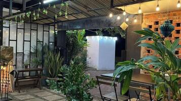 An outdoor patio area with seating, potted plants, and string lights.