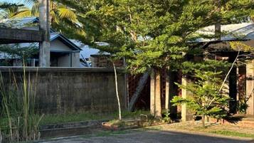 A residential area with a concrete wall, a tree, and a building with a sloped roof.