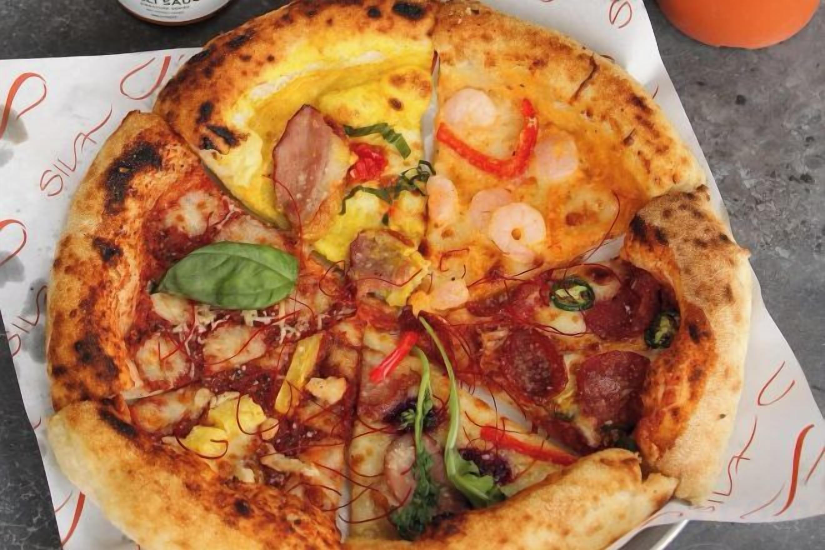 A pizza with various toppings on a white paper.