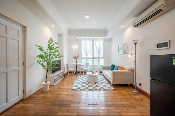 A modern living room with a sofa, coffee table, and a potted plant. - The Manor 2 studio- free rooftop pool and free pick up for 5 nights (Ho Chi Minh City)