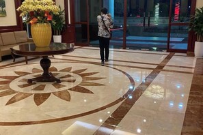 A lobby with a marble floor, a round table with a flower arrangement, and a glass door leading outside. - The Manor 2 studio- free rooftop pool and free pick up for 5 nights (Ho Chi Minh City)