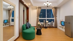 A modern living room with a green sofa, a round coffee table, a dining table with chairs, a large mirror, and a television. - The Manor 2 studio- free rooftop pool and free pick up for 5 nights (Ho Chi Minh City)