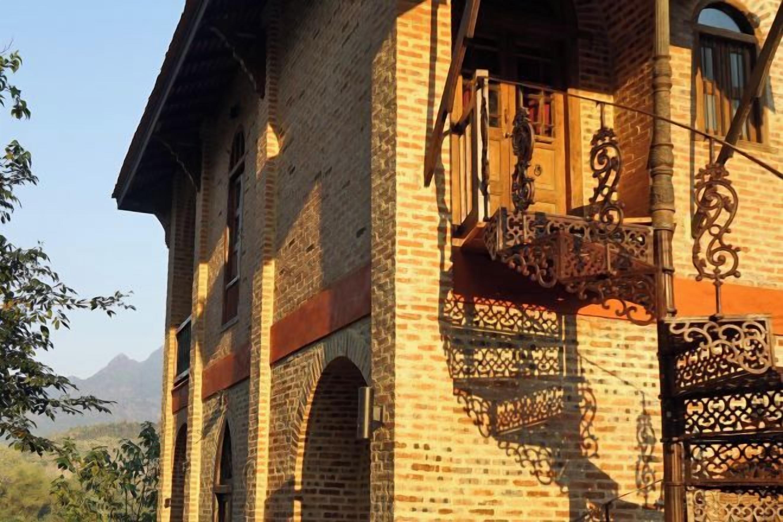Ein Backsteinhaus mit einem Balkon und kunstvollen Metallgeländern.
