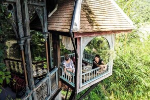 A wooden structure with a balcony, surrounded by greenery. - Chateau Orientale (Luang Prabang)