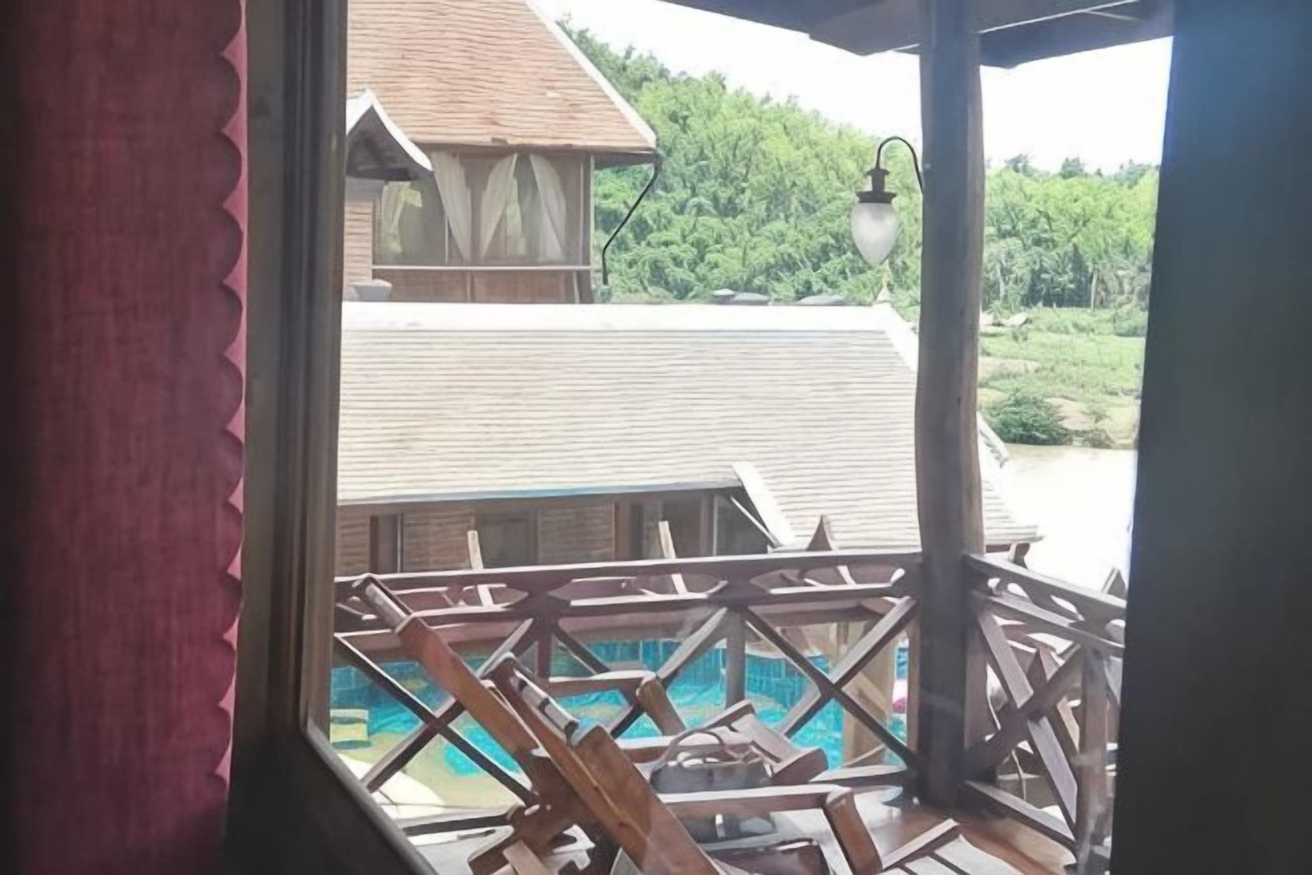Ein Holzbalkon mit Blick auf einen Swimmingpool und ein Gebäude mit einem geneigten Dach.