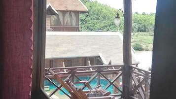 Ein Holzbalkon mit Blick auf einen Swimmingpool und ein Gebäude mit einem geneigten Dach.