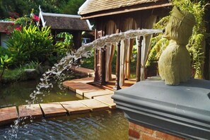 A water feature with a wooden deck and a stone structure. - Chateau Orientale (Luang Prabang)