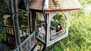 A wooden structure with a balcony, surrounded by greenery. - Chateau Orientale (Luang Prabang)