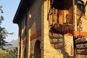 A brick building with ornate metalwork and arched windows. - Chateau Orientale (Luang Prabang)
