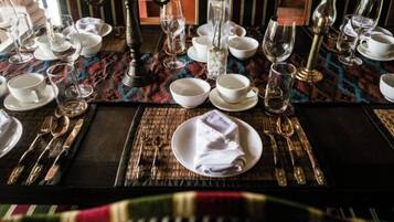 Une table dressée avec de l’assiette, des bols et des couverts blancs, des verres et un chandelier.