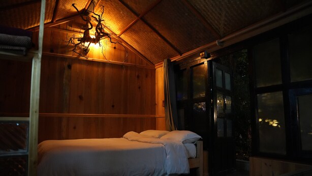 Una habitación de madera con una cama, una ventana y una lámpara colgante.