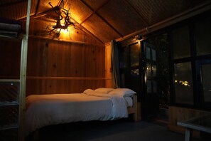 Une pièce en bois avec un lit, une fenêtre et un luminaire suspendu.