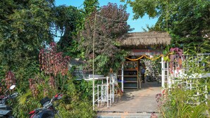Estructura con techo de paja y una escalera que lleva a una tienda, rodeada de abundante vegetación.