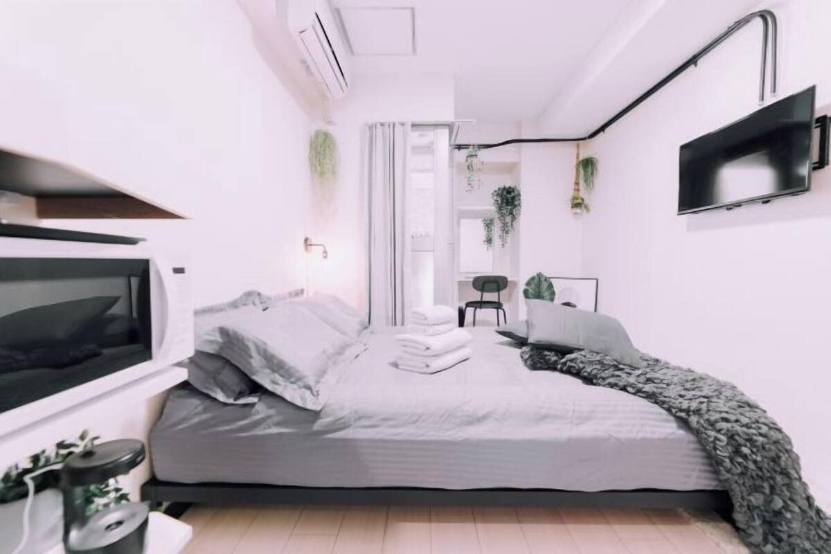 A modern bedroom with a bed, a TV, a desk, and a chair.