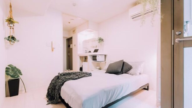 A modern bedroom with a bed, bedside tables, and a small desk with a chair. - Minimalist Loft 8: Namba Compact Studio & 24/7 Gym (Osaka)