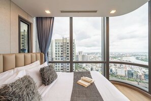 A modern hotel room with a large window, a bed with a headboard, and a view of the cityscape. - Condotel Imperial Landmark 81 (Ho Chi Minh City)