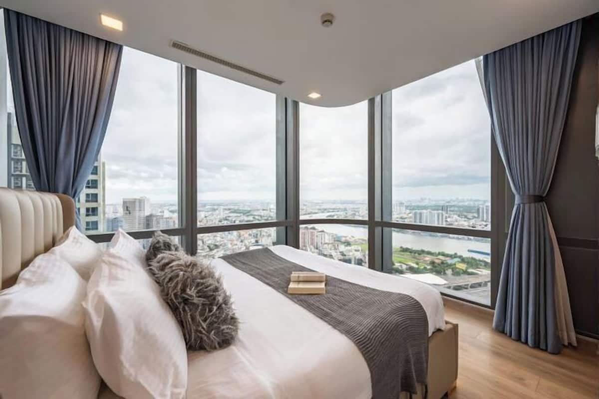 A modern bedroom with a large bed, a view of the city, and large windows.