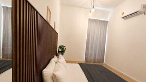 A bedroom with a bed, a wooden headboard, a potted plant, and a window with curtains. - Sunway NEXIS, Kota Damansara (Petaling Jaya)