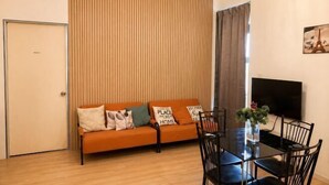 A modern living room with a sofa, a dining table with chairs, a TV, and a window with curtains. - Sunway NEXIS, Kota Damansara (Petaling Jaya)