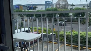 A balcony with a view of a street, a parking lot, and some greenery. - MOA Shell Residence tower A Kai’STAYCATION (Pasay)