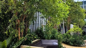 A garden area with a stone bench and dense foliage. - Tropicana 218 With Sea View by LS Staycation (George Town)