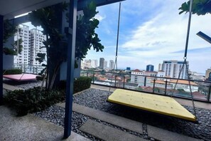 A rooftop terrace with a swing, seating, and a view of the cityscape. - Tropicana 218 With Sea View by LS Staycation (George Town)