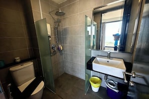 A bathroom with a toilet, a shower, a sink, and a mirror. - Tropicana 218 With Sea View by LS Staycation (George Town)