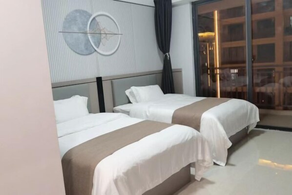 Hotellihuone, jossa on kaksi sänkyä, moderni seinäkello ja suuri ikkuna, josta on näkym ä kaupunkiin.