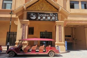 A building with a sign for a hotel and a vintage car parked in front. - Jizhou Hotel (Boten)