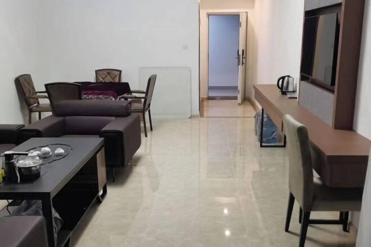 A modern living room with a sofa, chairs, a dining table, and a TV.