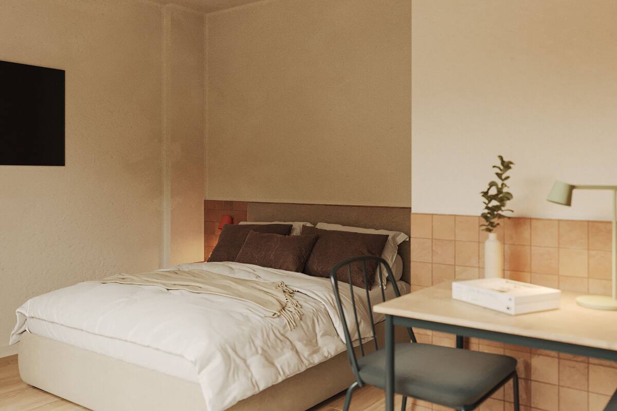 A bedroom with a bed, a desk, a chair, and a bedside table.