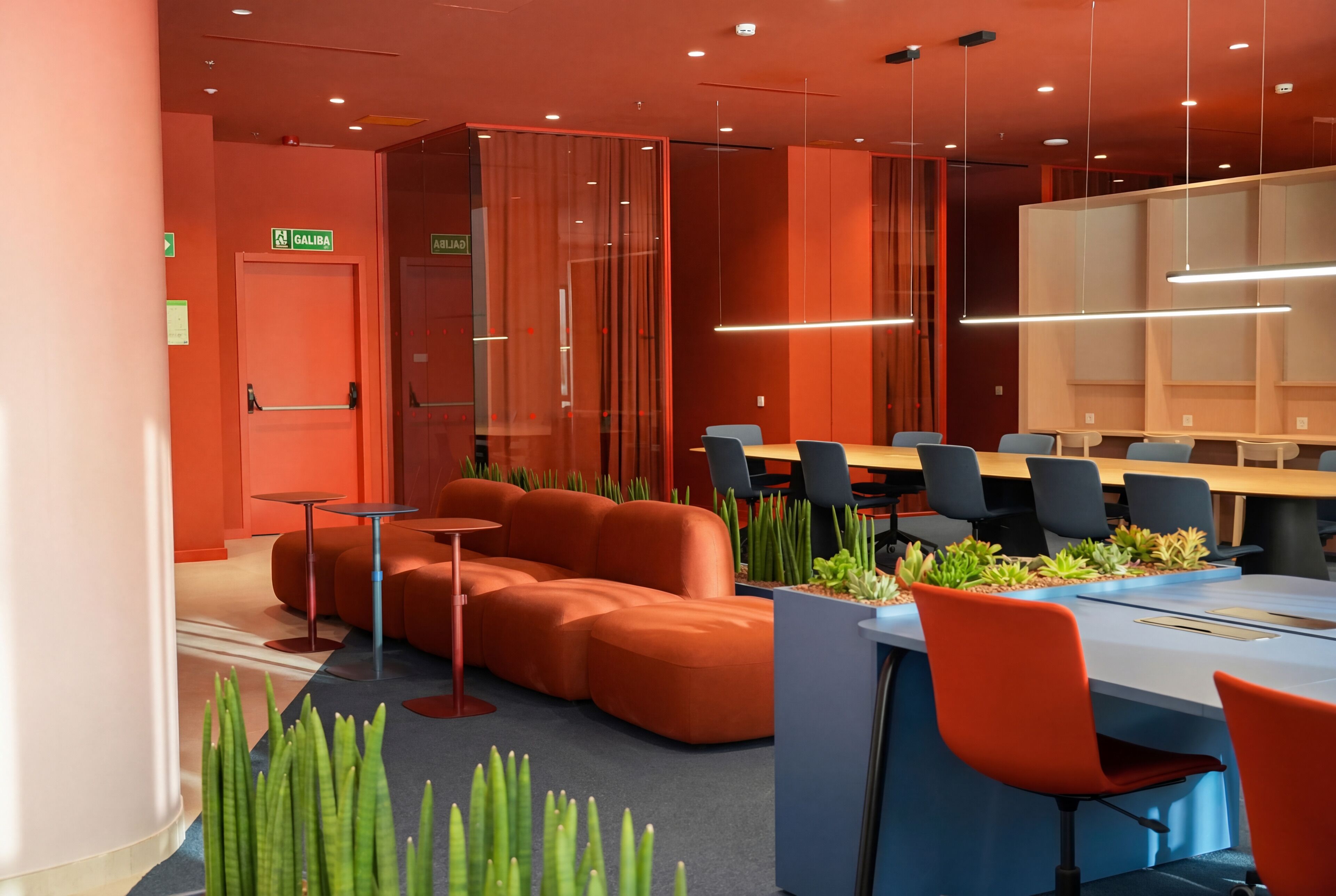 Une salle de conférence moderne, dotée d’une longue table, de sièges orange et de plantes vertes.