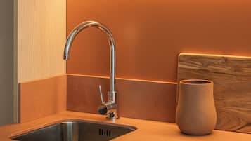 Una cocina moderna con un lavamanos de acero inoxidable, armarios de madera e iluminación cálida bajo los gabinetes.