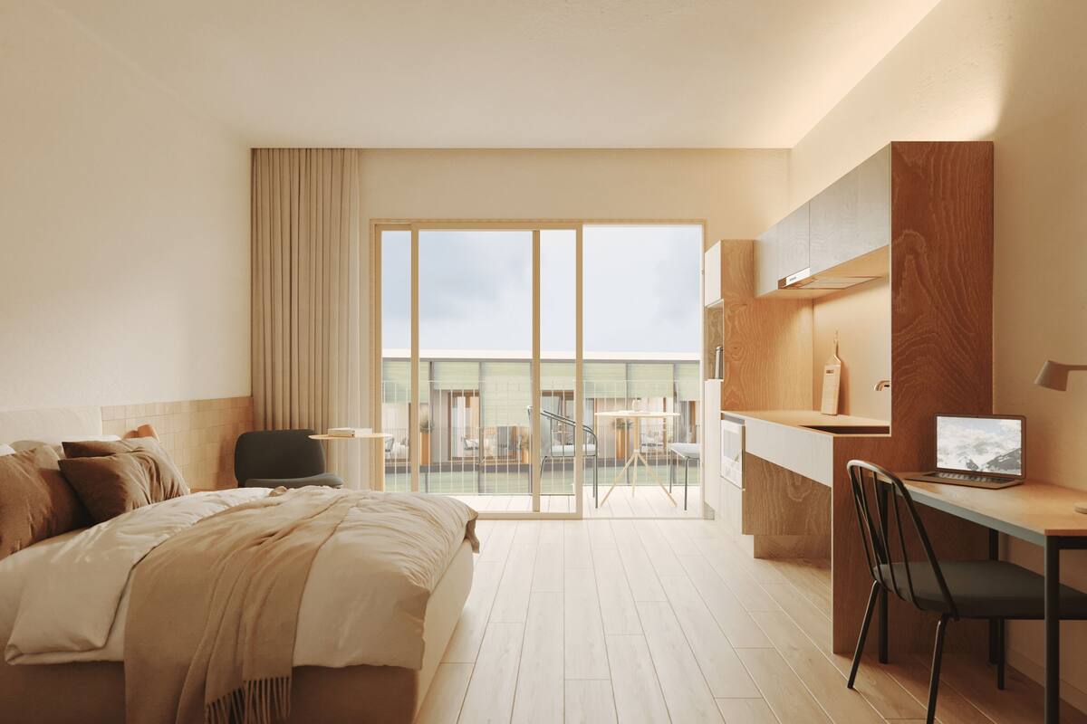 A hotel room with a bed, desk, chair, and a view of the outdoors.