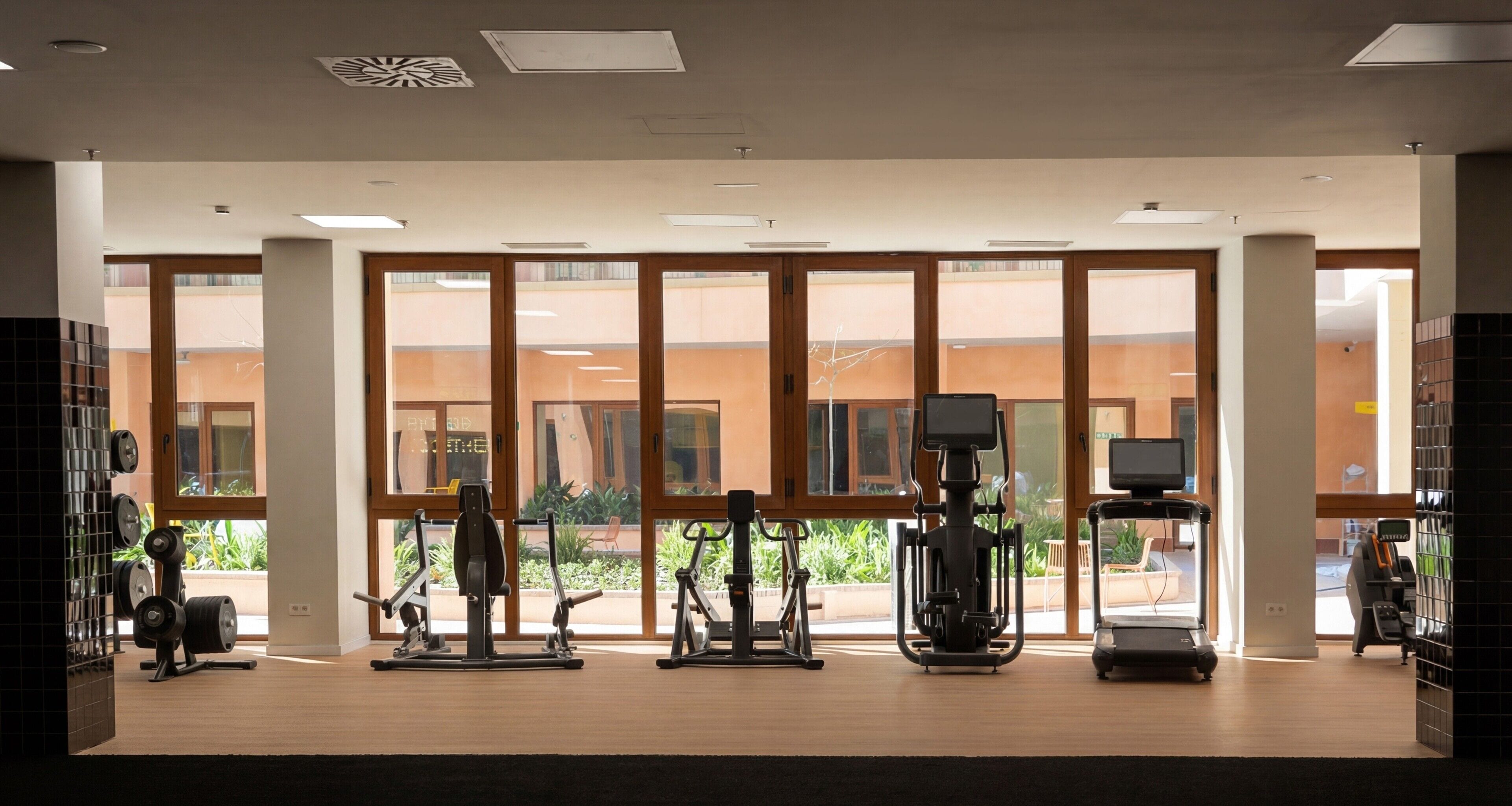 A gym with exercise equipment, large windows, and a view of the outside.