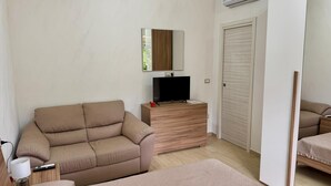A room with a beige sofa, a TV on a wooden stand, a mirror on the wall, and a wardrobe. - Marianna 's House newly renovated apartment in Naples near airport (Napoli)