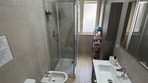 A modern bathroom with a glass-enclosed shower, a bidet, a toilet, and a large sink with a mirror. - Marianna 's House newly renovated apartment in Naples near airport (Napoli)