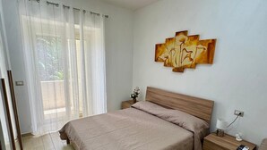 A bedroom with a large bed, a nightstand, a bedside table, a lamp, and a wall art piece. - Marianna 's House newly renovated apartment in Naples near airport (Napoli)